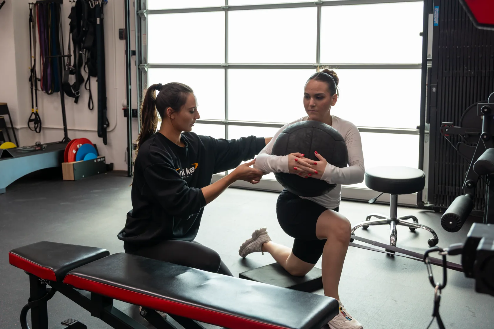 A Prehab physical therapist guiding a patient through a kneeling medicine-ball exercise