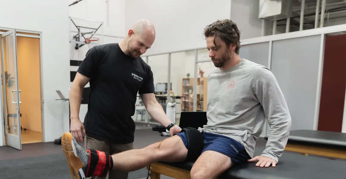 A [P]rehab clinician coaching a patient through a weighted knee extension in the Los Angeles clinic