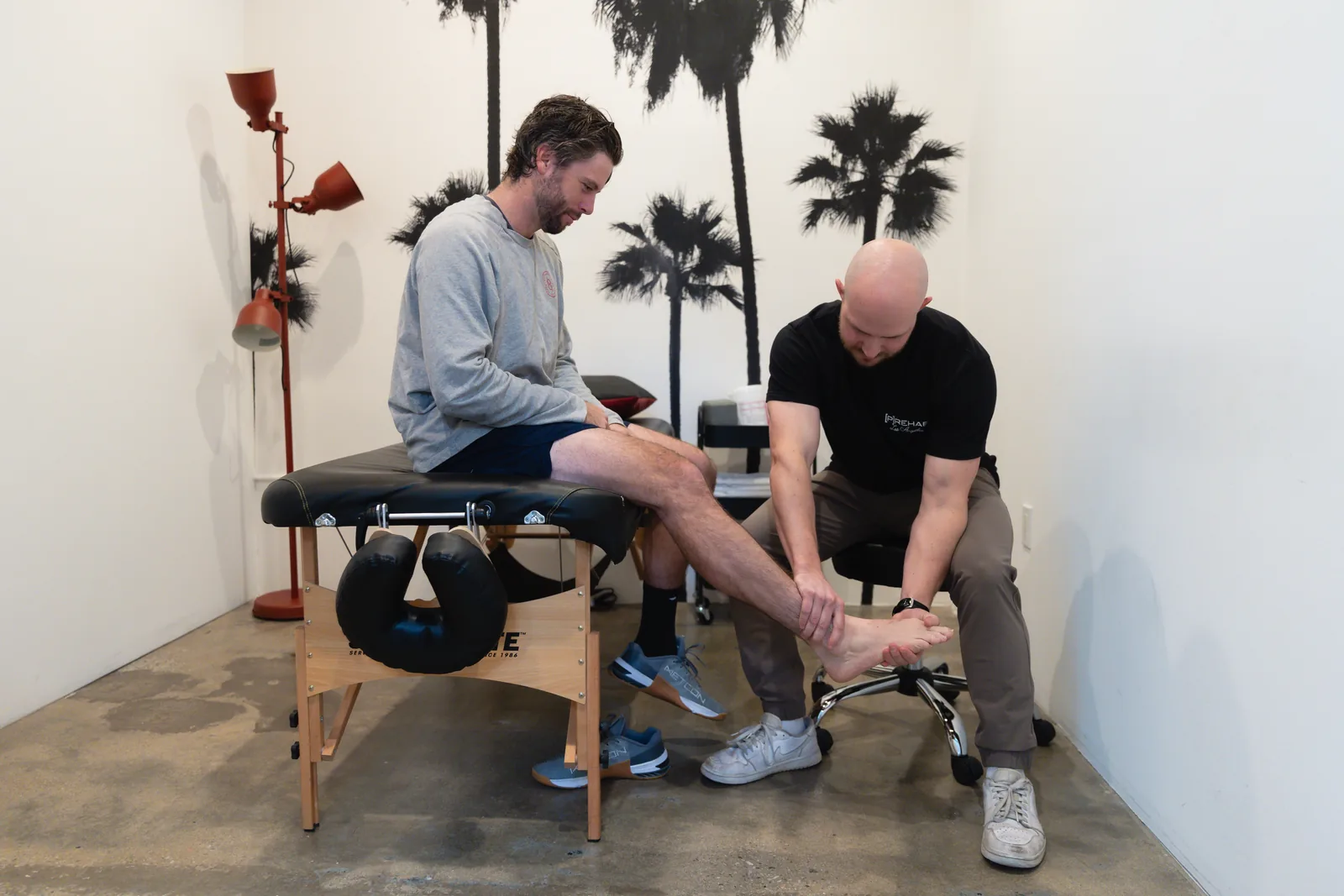 A Prehab clinician assessing a patient's ankle in the Culver City clinic